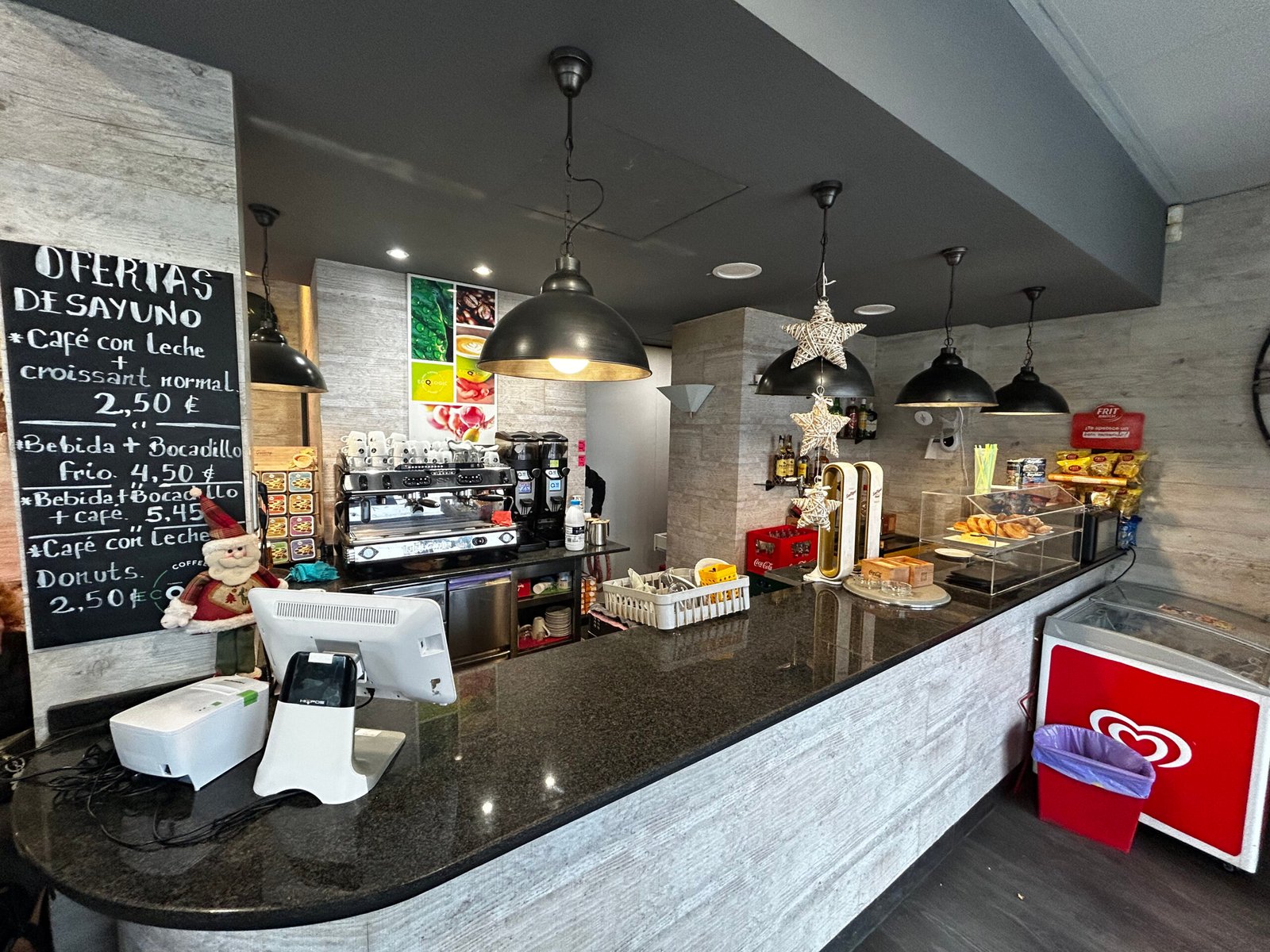 Zona de cafetería y barra con bollería, cerveza artesanal y opciones de desayuno